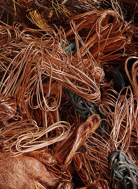 A tangled pile of shiny, loose copper wires in various loops and coils, creating a dense, chaotic texture with reddish-brown and metallic hues.
